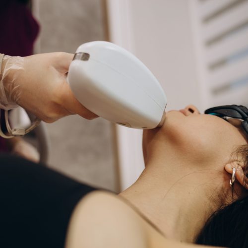 Elos epilation hair removal procedure on the face of a woman. Beautician doing laser rejuvenation on the neck in a beauty salon. Facial skin care. Hardware ipl cosmetology